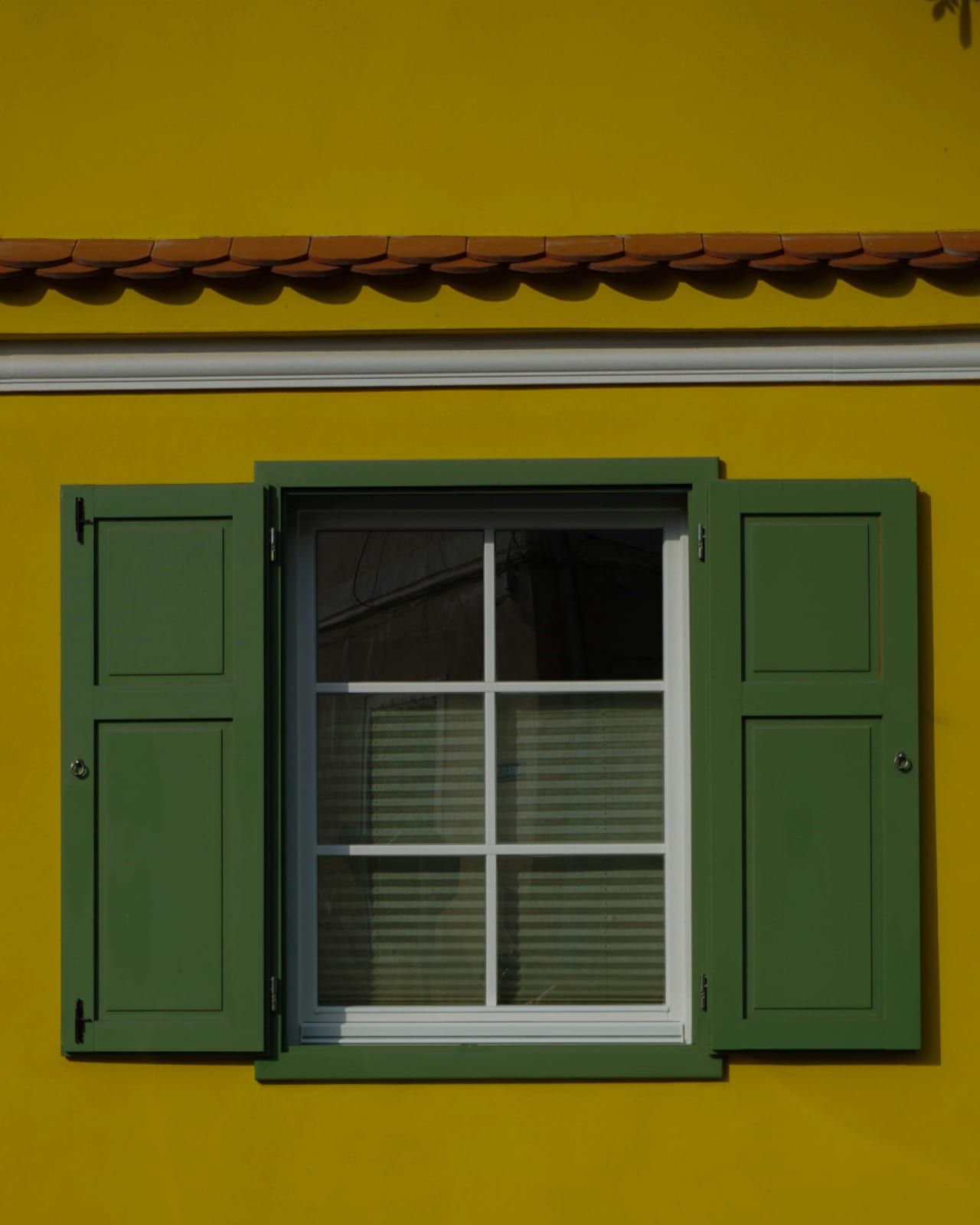 Contraventanas verdes cerradas en una fachada de piedra