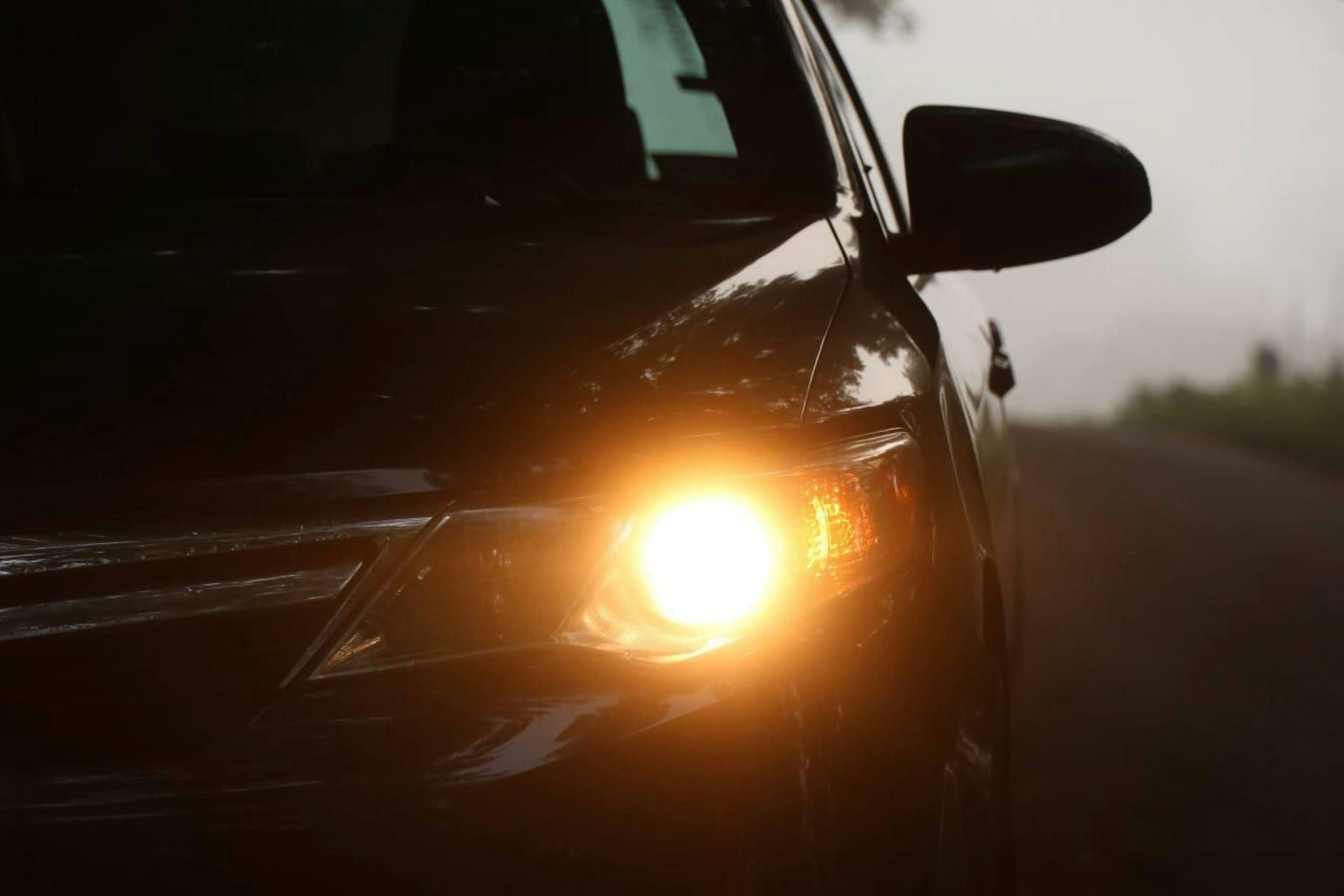 El faro encendido de un coche oscuro al atardecer