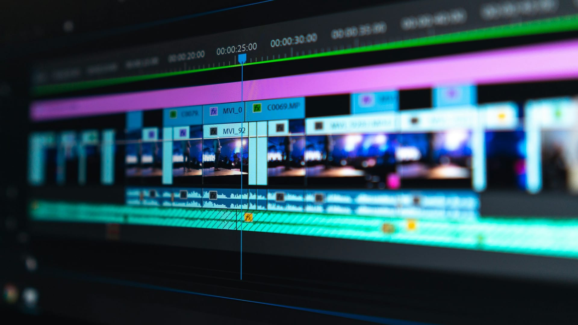 Una línea de tiempo de edición de vídeo en una pantalla oscura, con los clips en azul y morado