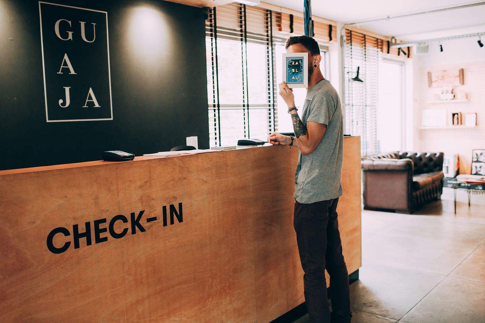 Un hombre en el mostrador de recepción de un hotel con el letrero «Check-in»