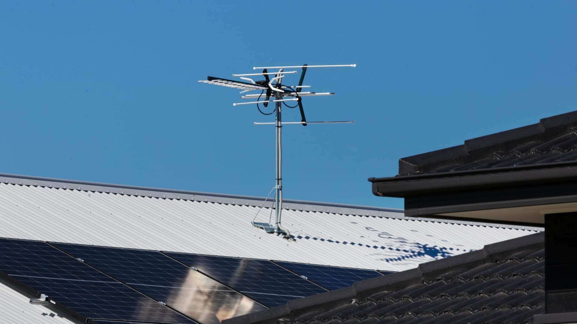 Una antena de televisión en un tejado, contra un cielo azul limpio