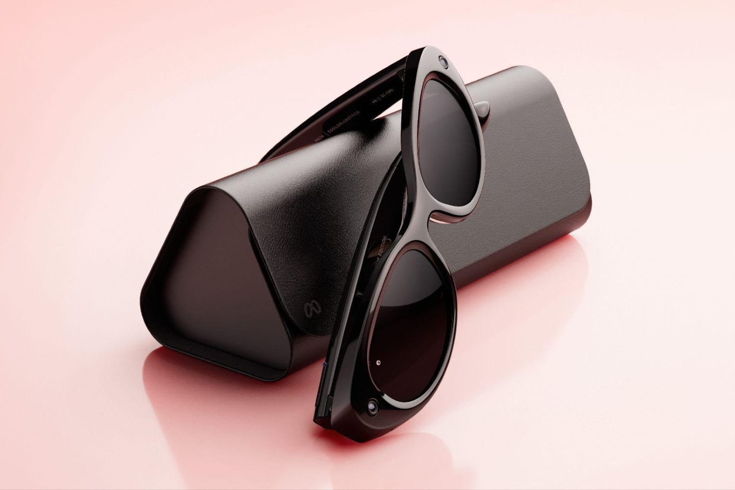 Unas gafas de Meta negras apoyadas sobre su estuche de carga, sobre fondo rosa