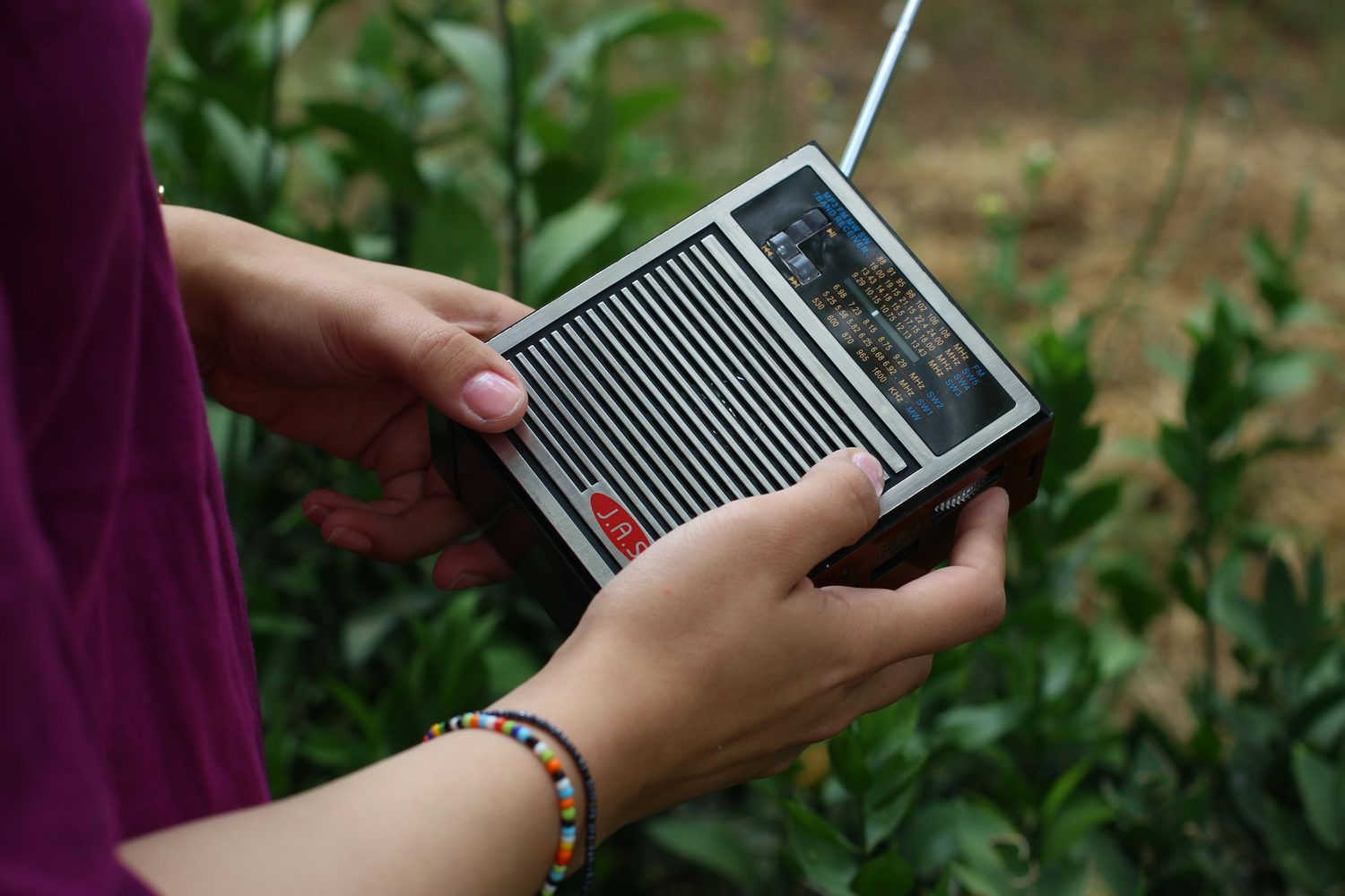 Unas manos sujetando una radio portátil de pilas con la antena desplegada
