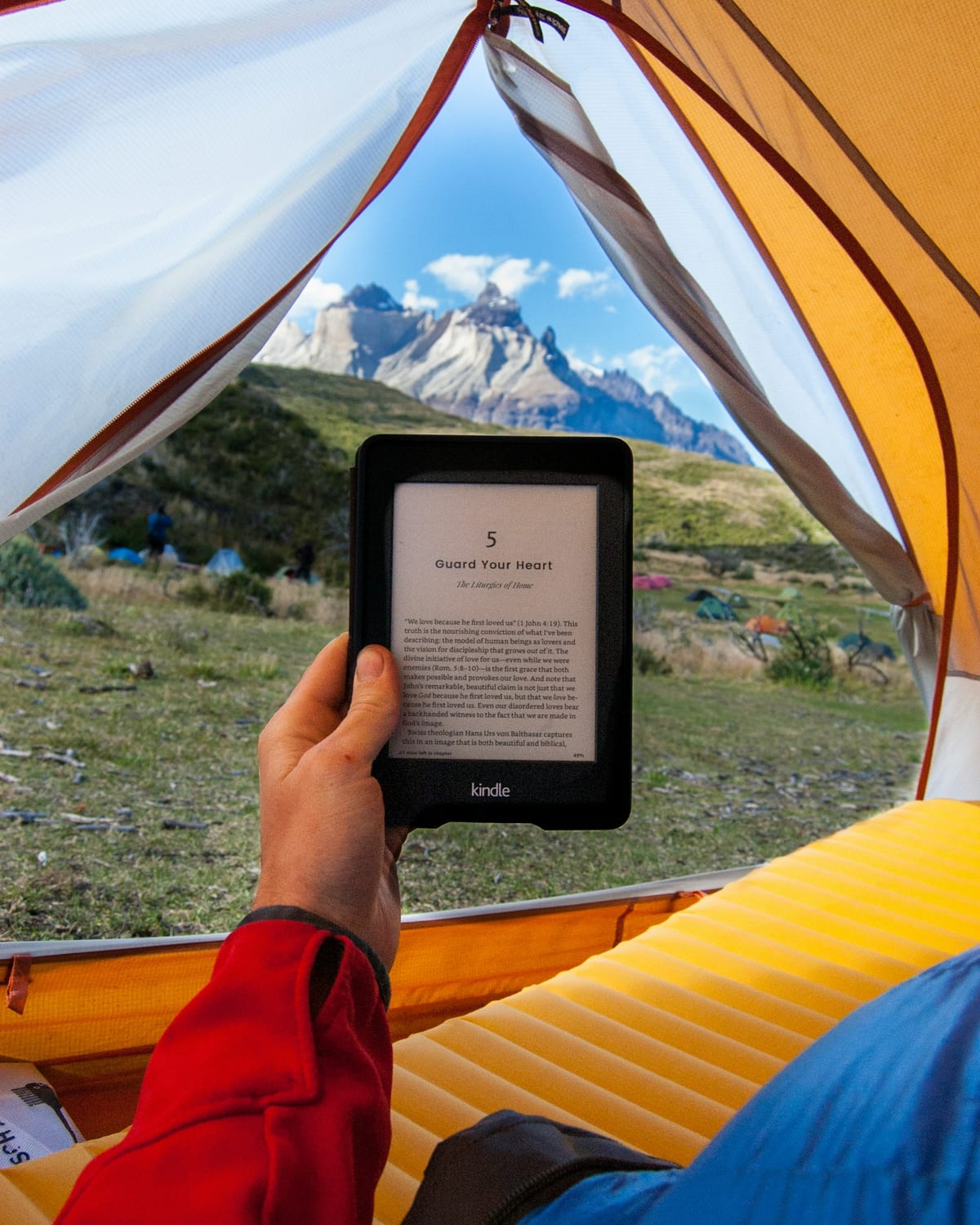 Un libro electrónico dentro de una tienda de campaña con montañas al fondo