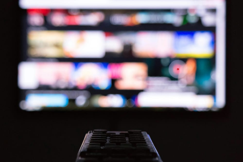 Mando a distancia delante de un televisor encendido en una habitación a oscuras