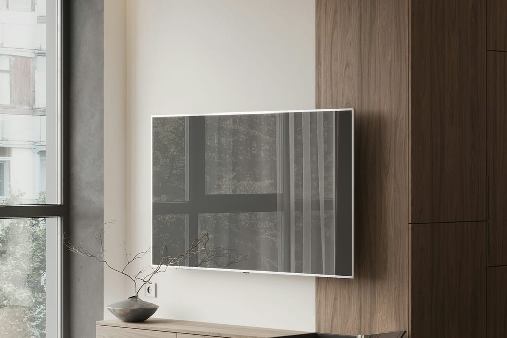 Televisor colgado en la pared junto a una ventana, con el reflejo de la luz en la pantalla