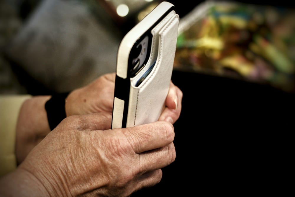 Manos de una persona mayor sujetando un móvil con funda de cartera