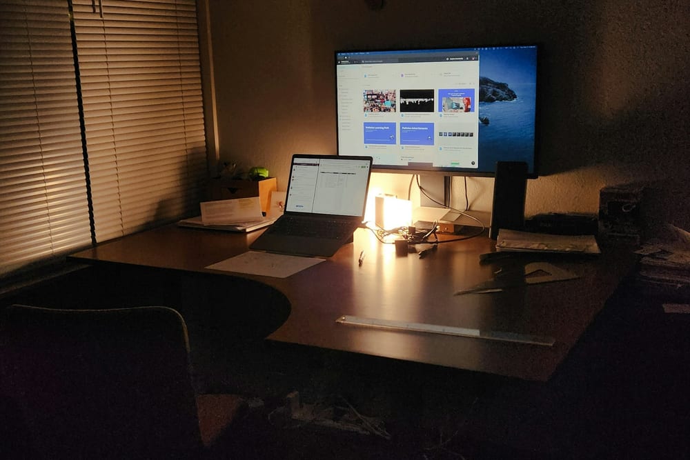 Escritorio en penumbra con un portátil conectado a un monitor