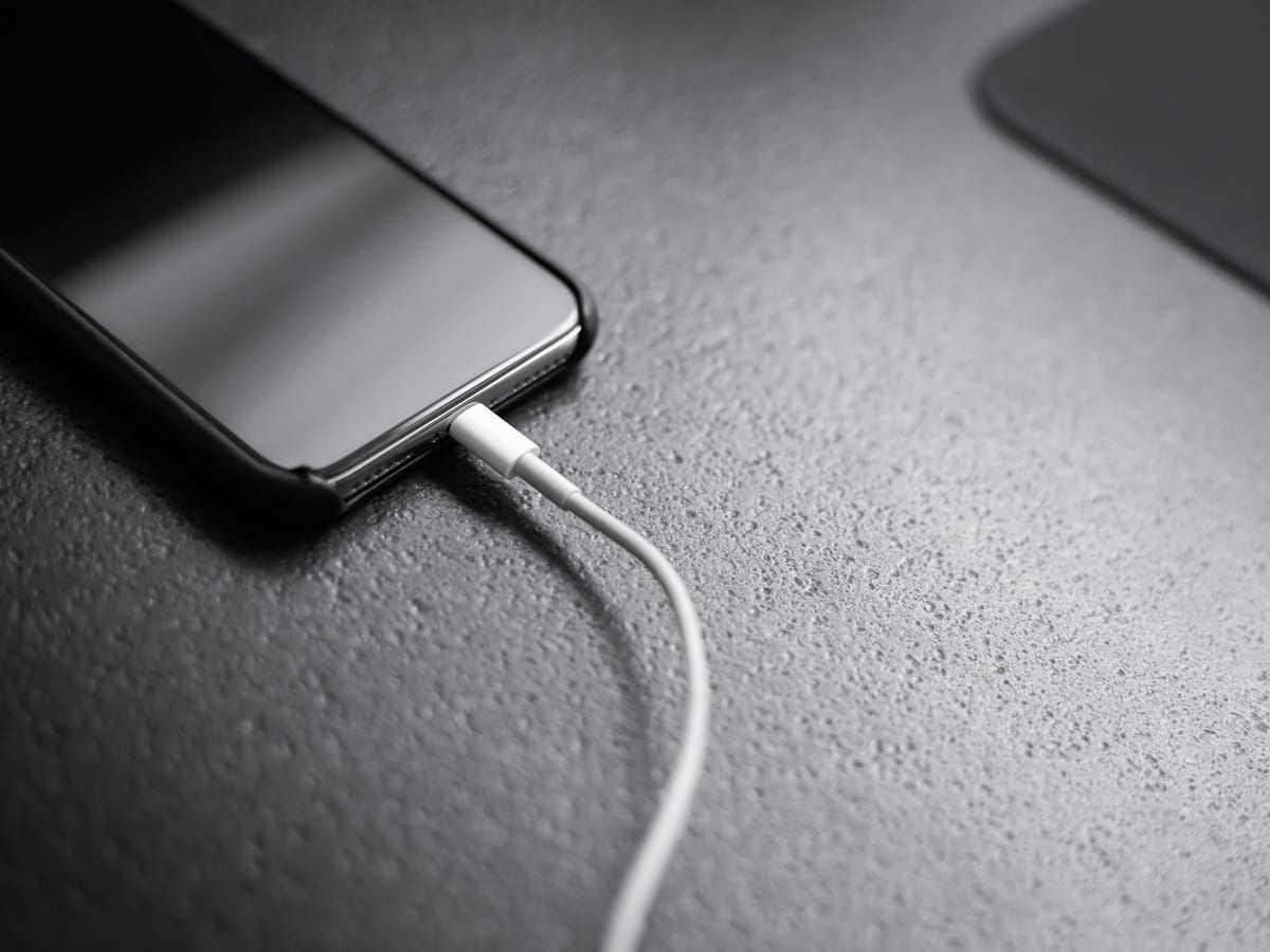Un móvil cargando sobre una mesa oscura con un cable blanco