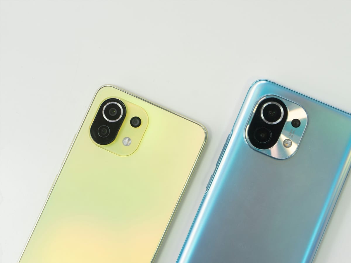 Dos móviles Xiaomi parecidos, uno amarillo verdoso y otro azul claro, sobre una mesa blanca