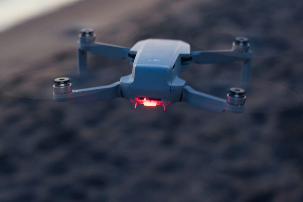Un dron pequeño vuela sobre la arena de una playa al atardecer