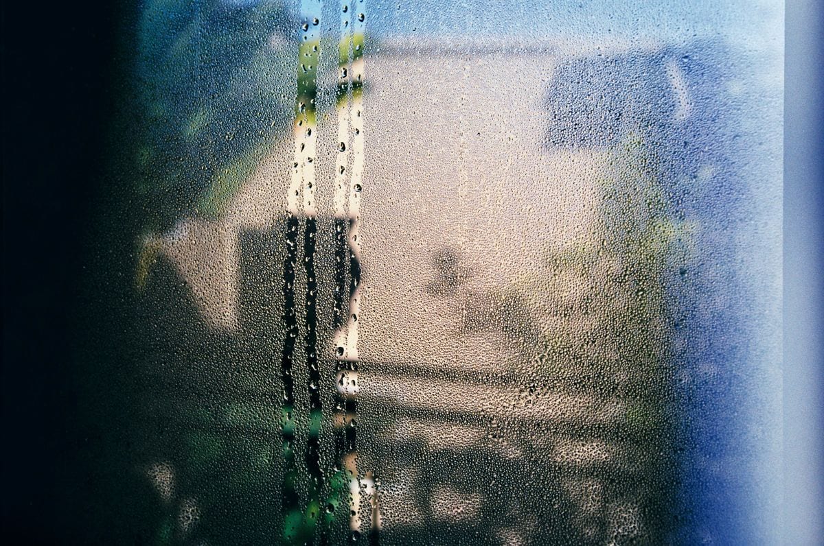Cristal de una ventana cubierto de vaho con gotas que resbalan