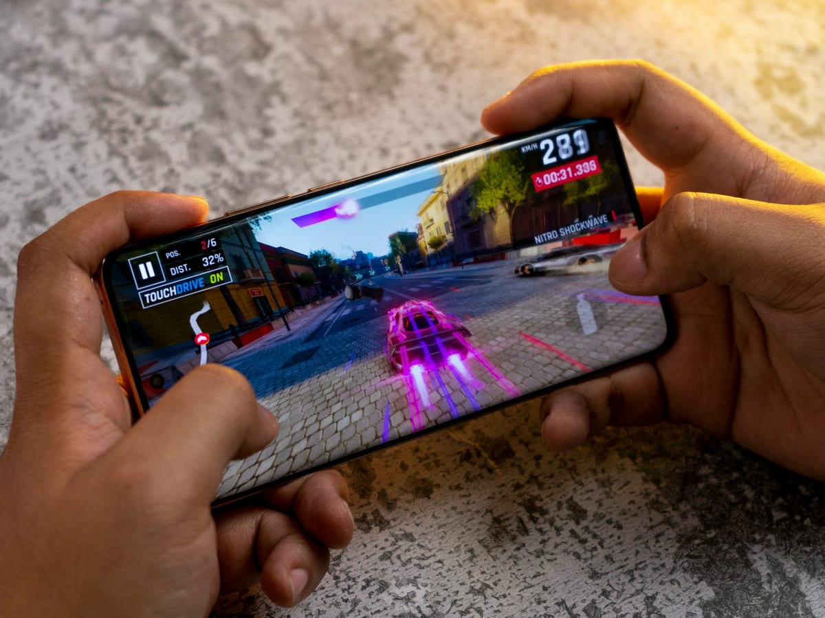 Dos manos sujetando un móvil en horizontal con un juego de carreras en la pantalla
