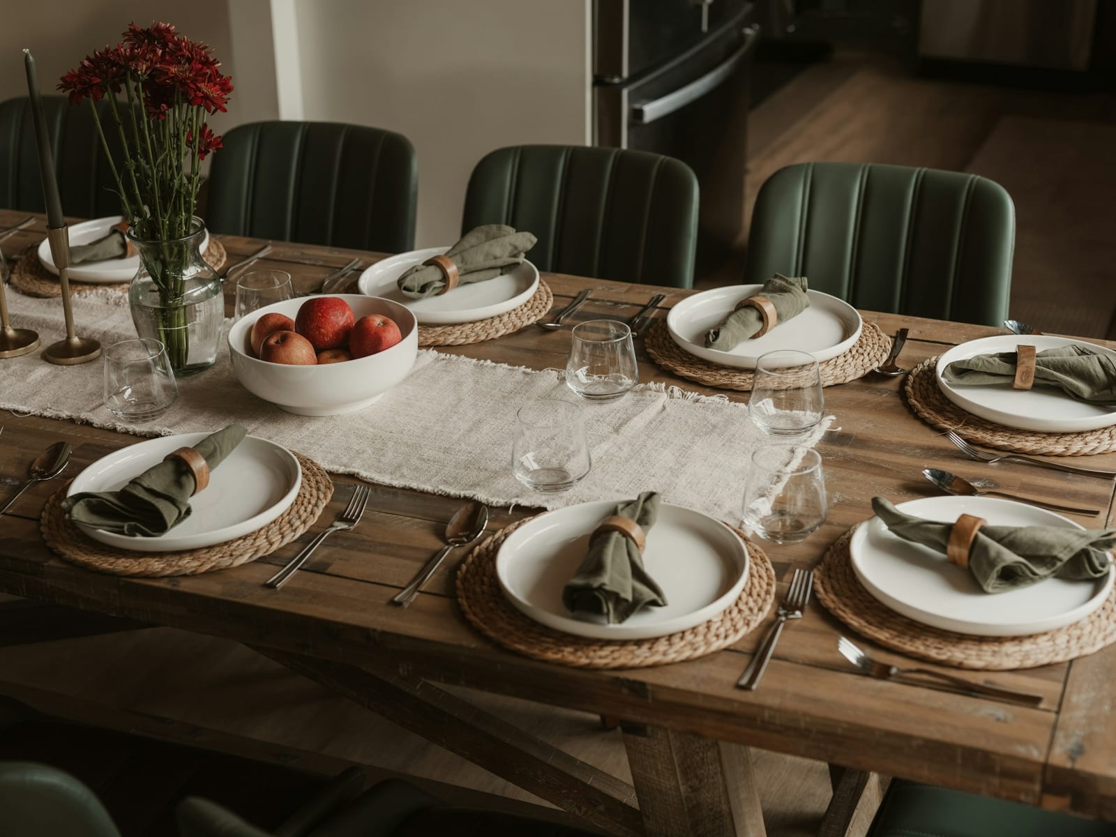 Mesa de madera puesta para seis con platos blancos y servilletas verdes