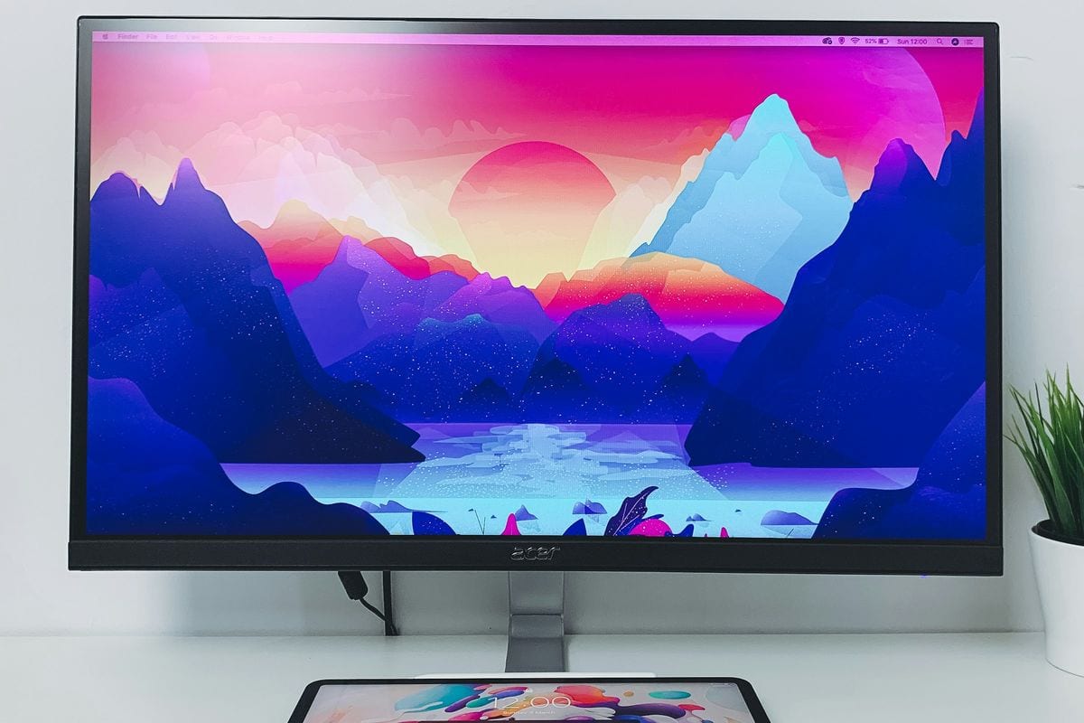 Monitor sobre una mesa blanca con un paisaje de colores en la pantalla