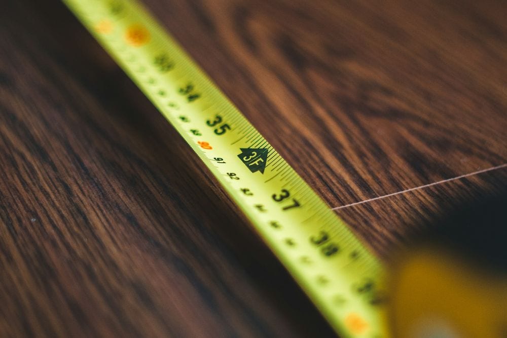 Cinta métrica amarilla extendida sobre una mesa de madera oscura