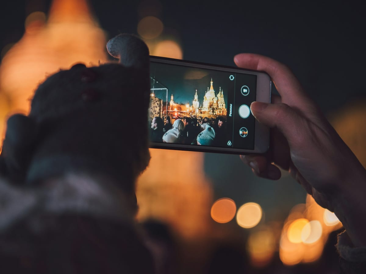 Persona fotografiando con el móvil un edificio iluminado de noche