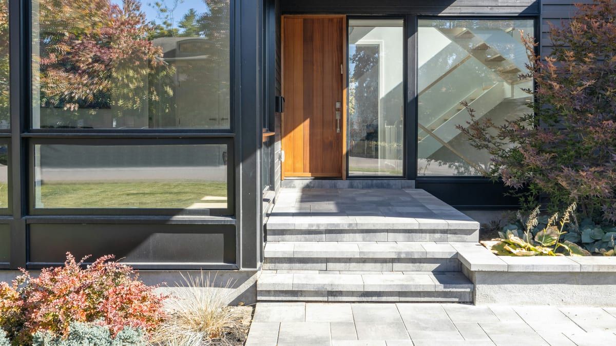 Entrada de una casa moderna con escalones de piedra y una puerta de madera
