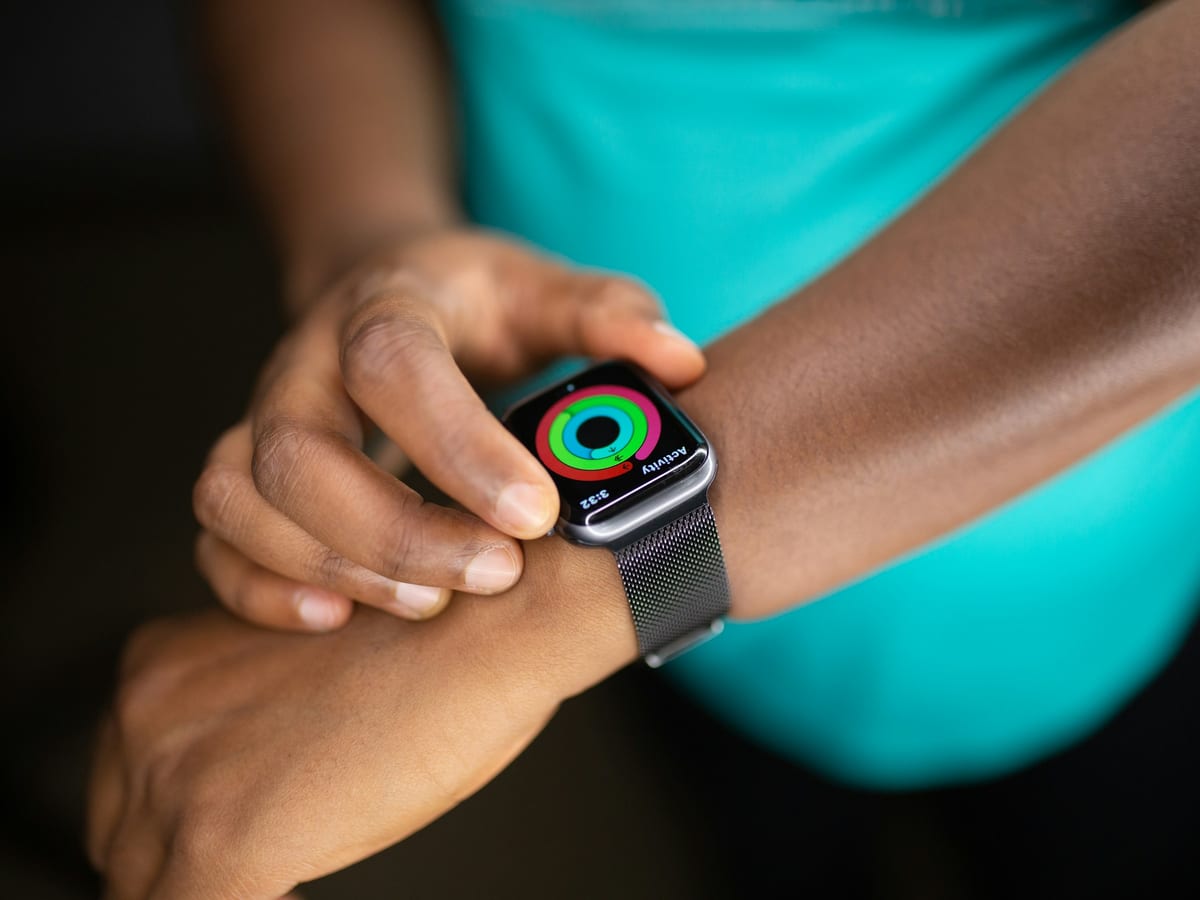 Los anillos de actividad en la pantalla de un Apple Watch, en la muñeca de una persona con ropa de deporte