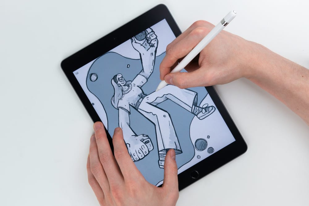 Manos dibujando con un Apple Pencil la ilustración de una persona en un iPad