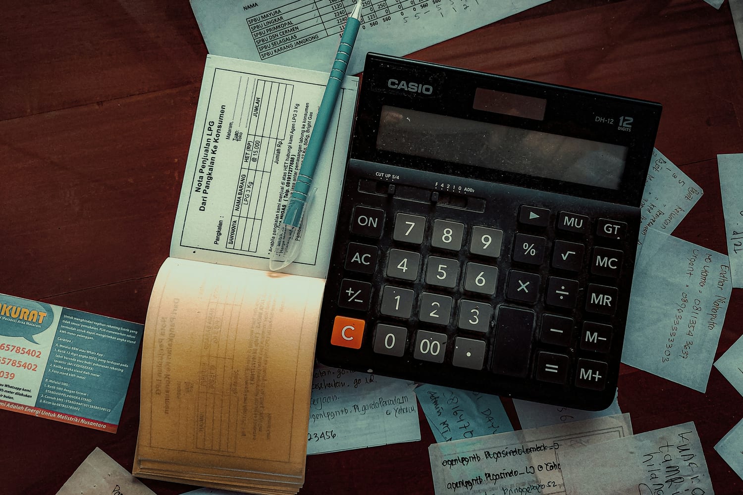 Un talonario de facturas abierto junto a una calculadora sobre una mesa de madera